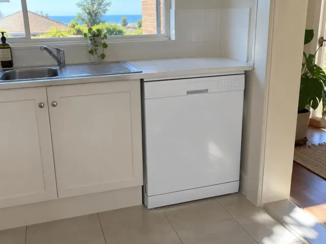 Kitchen sink and built-in dishwasher under a white benchtop in a bright home in Merewether