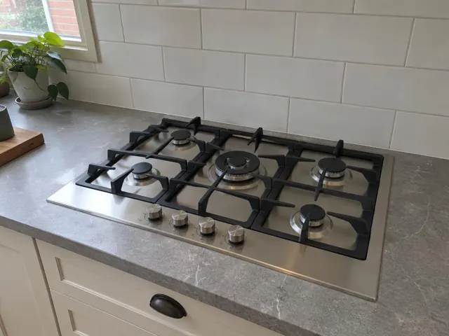 Built-in gas cooktop in a grey benchtop with tiled splashback and white cabinetry in Broadmeadow
